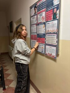 Grupa wychowanków bursy szkolnej prezentuje plakaty informacyjne dotyczące depresji oraz hasło „Stop depresji”. Na kolejnych zdjęciach jedna z uczestniczek przypina materiały edukacyjne na tablicy informacyjnej na korytarzu bursy. Plansze zawierają informacje o objawach depresji, sposobach szukania pomocy oraz profilaktyce.