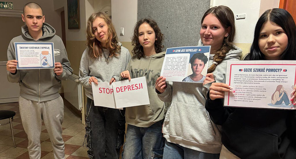Grupa wychowanków bursy szkolnej prezentuje plakaty informacyjne dotyczące depresji oraz hasło „Stop depresji”. Na kolejnych zdjęciach jedna z uczestniczek przypina materiały edukacyjne na tablicy informacyjnej na korytarzu bursy. Plansze zawierają informacje o objawach depresji, sposobach szukania pomocy oraz profilaktyce.