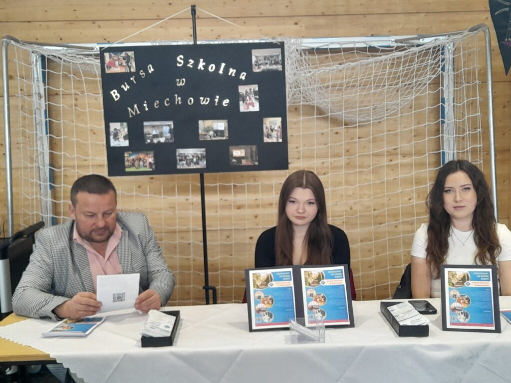 Stoisko Bursy Szkolnej w Miechowie podczas Powiatowych Targów Edukacji – przedstawiciele bursy udzielają informacji odwiedzającym, prezentują materiały promocyjne oraz odpowiadają na pytania dotyczące warunków pobytu i oferty placówki