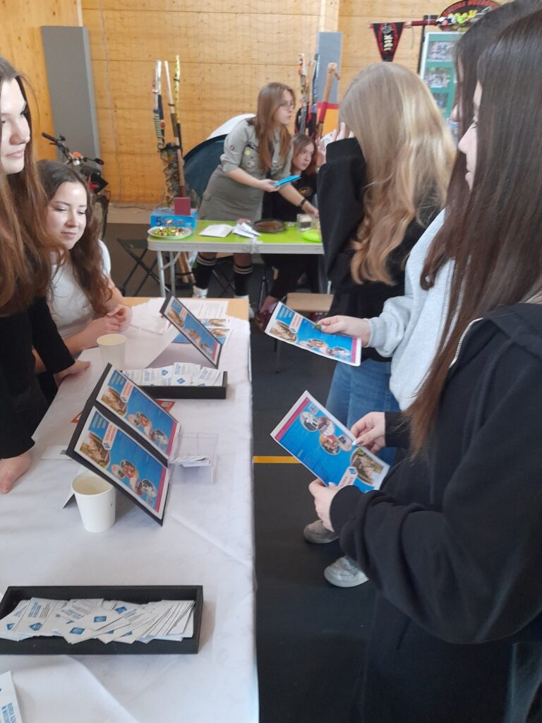 Stoisko Bursy Szkolnej w Miechowie podczas Powiatowych Targów Edukacji – przedstawiciele bursy udzielają informacji odwiedzającym, prezentują materiały promocyjne oraz odpowiadają na pytania dotyczące warunków pobytu i oferty placówki