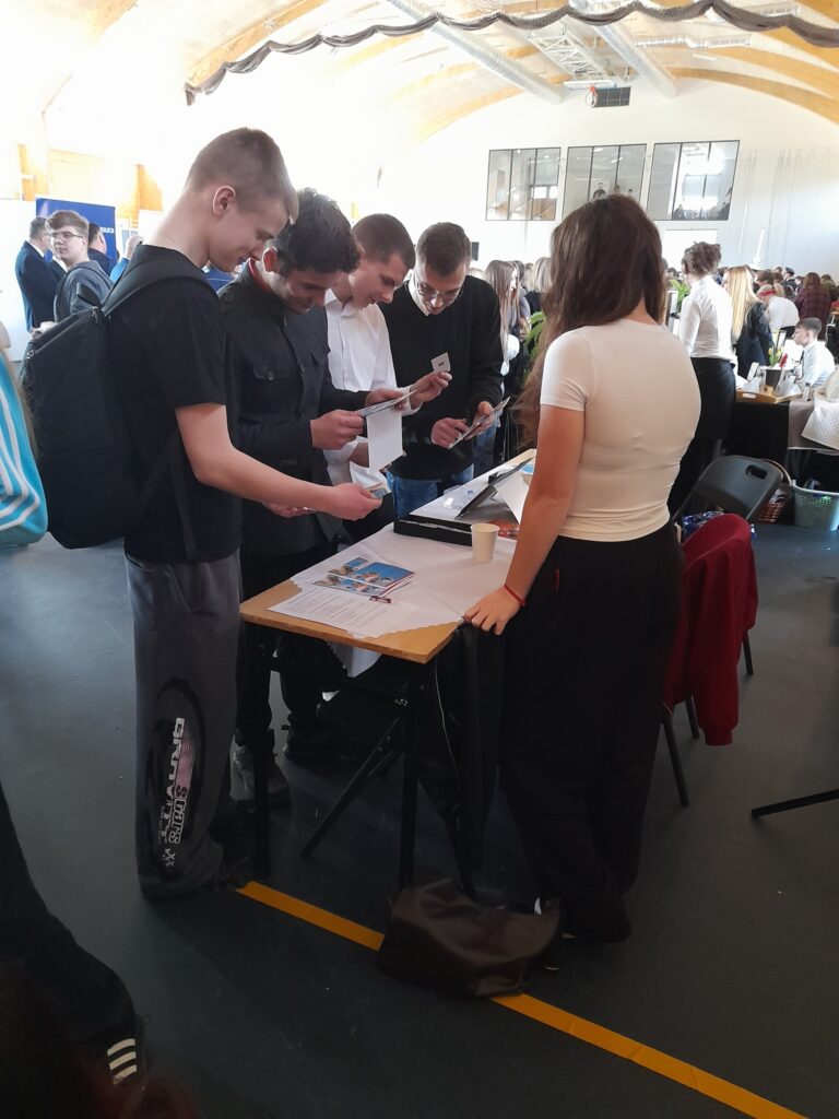Stoisko Bursy Szkolnej w Miechowie podczas Powiatowych Targów Edukacji – przedstawiciele bursy udzielają informacji odwiedzającym, prezentują materiały promocyjne oraz odpowiadają na pytania dotyczące warunków pobytu i oferty placówki