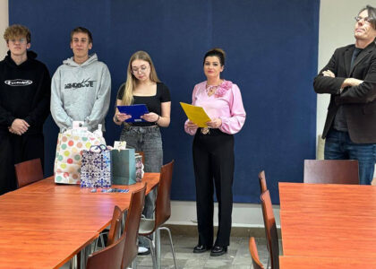 Zdjęcia przedstawiają uroczystość pożegnania maturzystów w Bursie Szkolnej. W sali z ustawionymi stołami i krzesłami grupa młodzieży oraz wychowawcy uczestniczą w oficjalnym spotkaniu. Na jednej z fotografii uczennica trzyma upominek, na innych widoczne jest wręczanie prezentów oraz odczytywanie przemówień i podziękowań. Na stołach znajdują się torby z upominkami. W tle widoczna jest tablica oraz elementy wyposażenia sali. Atmosfera wydarzenia ma charakter uroczysty i podniosły