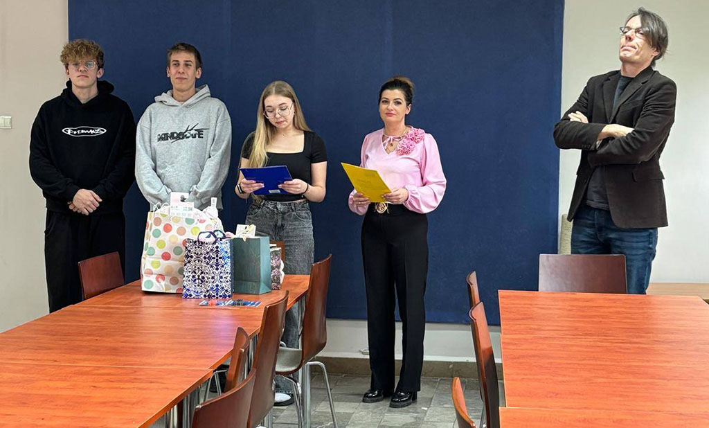 Zdjęcia przedstawiają uroczystość pożegnania maturzystów w Bursie Szkolnej. W sali z ustawionymi stołami i krzesłami grupa młodzieży oraz wychowawcy uczestniczą w oficjalnym spotkaniu. Na jednej z fotografii uczennica trzyma upominek, na innych widoczne jest wręczanie prezentów oraz odczytywanie przemówień i podziękowań. Na stołach znajdują się torby z upominkami. W tle widoczna jest tablica oraz elementy wyposażenia sali. Atmosfera wydarzenia ma charakter uroczysty i podniosły