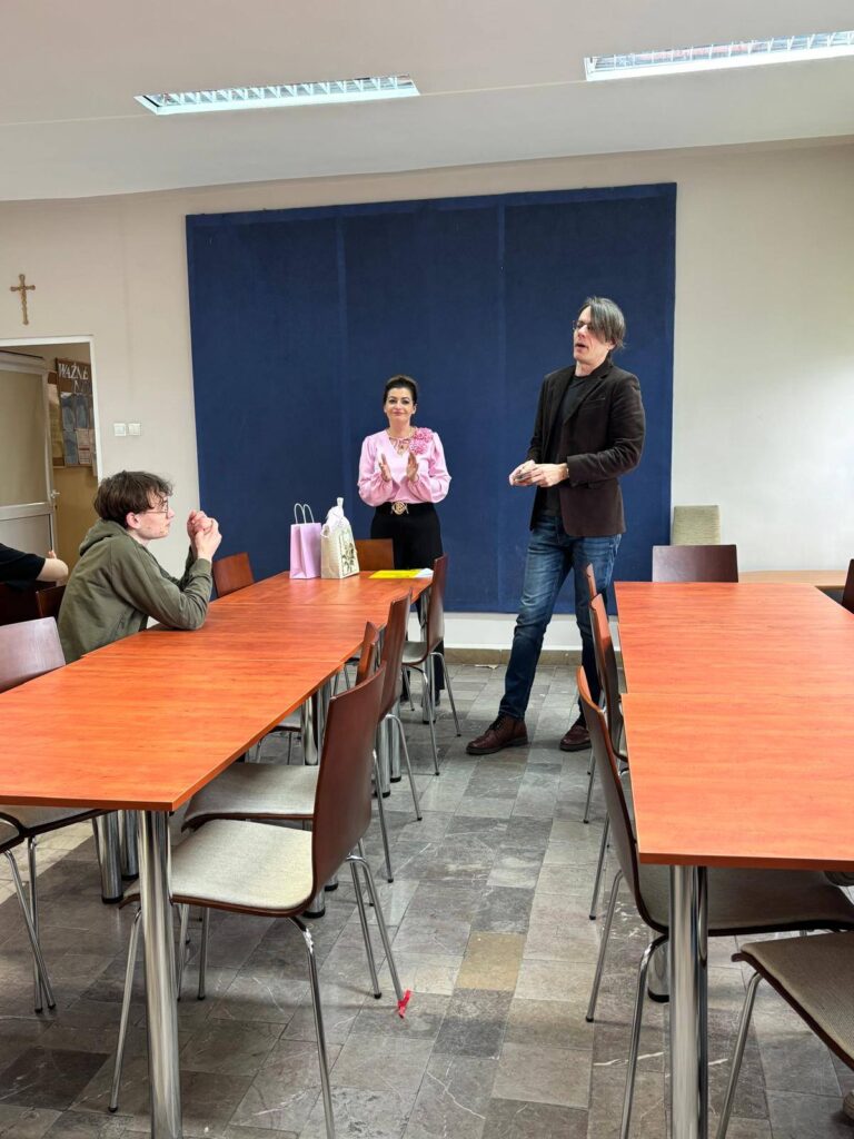 Zdjęcia przedstawiają uroczystość pożegnania maturzystów w Bursie Szkolnej. W sali z ustawionymi stołami i krzesłami grupa młodzieży oraz wychowawcy uczestniczą w oficjalnym spotkaniu. Na jednej z fotografii uczennica trzyma upominek, na innych widoczne jest wręczanie prezentów oraz odczytywanie przemówień i podziękowań. Na stołach znajdują się torby z upominkami. W tle widoczna jest tablica oraz elementy wyposażenia sali. Atmosfera wydarzenia ma charakter uroczysty i podniosły