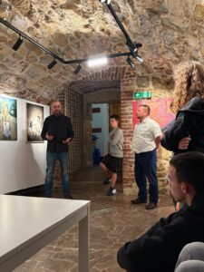 Zdjęcia przedstawiają młodzież z Bursy Szkolnej podczas wizyty w Galerii u Jaksy. Wychowankowie zwiedzają wystawę malarstwa, oglądają prezentowane dzieła oraz uczestniczą w spotkaniu z przewodnikiem, który przybliża historię i techniki tworzenia prezentowanych obrazów. Fotografie ukazują wnętrza galerii, ekspozycję dzieł sztuki oraz wspólne zwiedzanie wystawy.