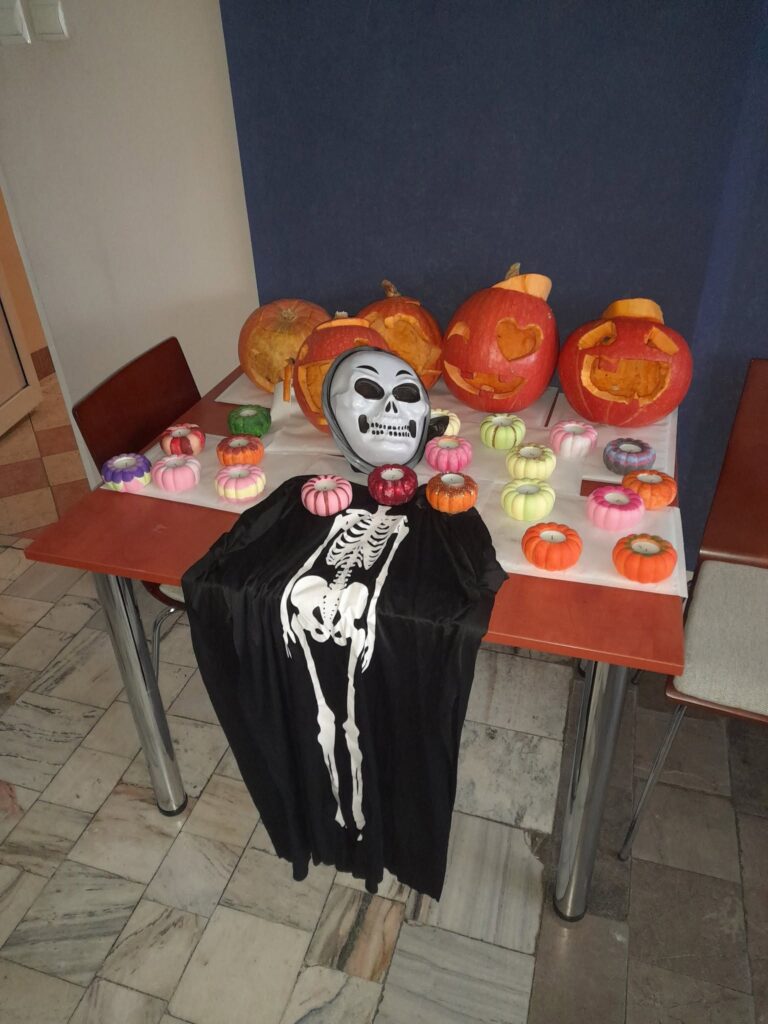 Wychowankowie Bursy Szkolnej w Miechowie podczas warsztatów artystyczno-integracyjnych z okazji Halloween. Zdjęcia przedstawiają zbieranie dyń w gospodarstwie rolnym, tworzenie halloweenowych lampionów, malowanie ozdób gipsowych oraz wspólną pracę i integrację młodzieży podczas zajęć.
