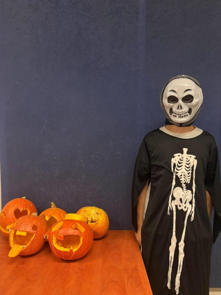 Wychowankowie Bursy Szkolnej w Miechowie podczas warsztatów artystyczno-integracyjnych z okazji Halloween. Zdjęcia przedstawiają zbieranie dyń w gospodarstwie rolnym, tworzenie halloweenowych lampionów, malowanie ozdób gipsowych oraz wspólną pracę i integrację młodzieży podczas zajęć.