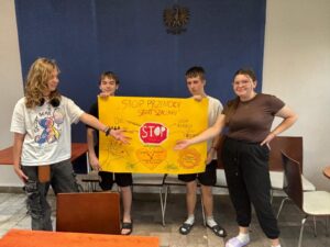 Czworo wychowanków Bursy Szkolnej prezentuje wspólnie przygotowany plakat „Stop przemocy, start szacunku”, promujący przeciwdziałanie przemocy, szacunek i wzajemną pomoc.