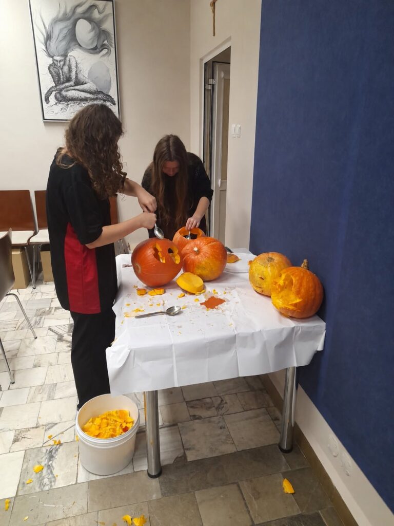 Wychowankowie Bursy Szkolnej w Miechowie podczas warsztatów artystyczno-integracyjnych z okazji Halloween. Zdjęcia przedstawiają zbieranie dyń w gospodarstwie rolnym, tworzenie halloweenowych lampionów, malowanie ozdób gipsowych oraz wspólną pracę i integrację młodzieży podczas zajęć.