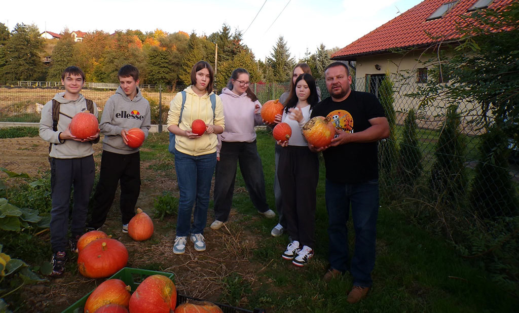 Wychowankowie Bursy Szkolnej w Miechowie podczas warsztatów artystyczno-integracyjnych z okazji Halloween. Zdjęcia przedstawiają zbieranie dyń w gospodarstwie rolnym, tworzenie halloweenowych lampionów, malowanie ozdób gipsowych oraz wspólną pracę i integrację młodzieży podczas zajęć.