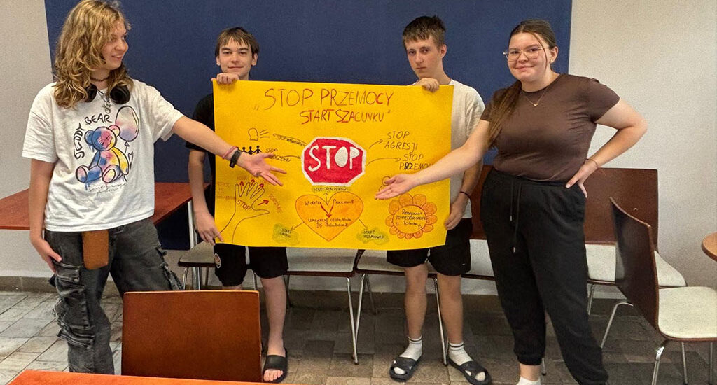 Czworo wychowanków Bursy Szkolnej prezentuje wspólnie przygotowany plakat „Stop przemocy, start szacunku”, promujący przeciwdziałanie przemocy, szacunek i wzajemną pomoc.